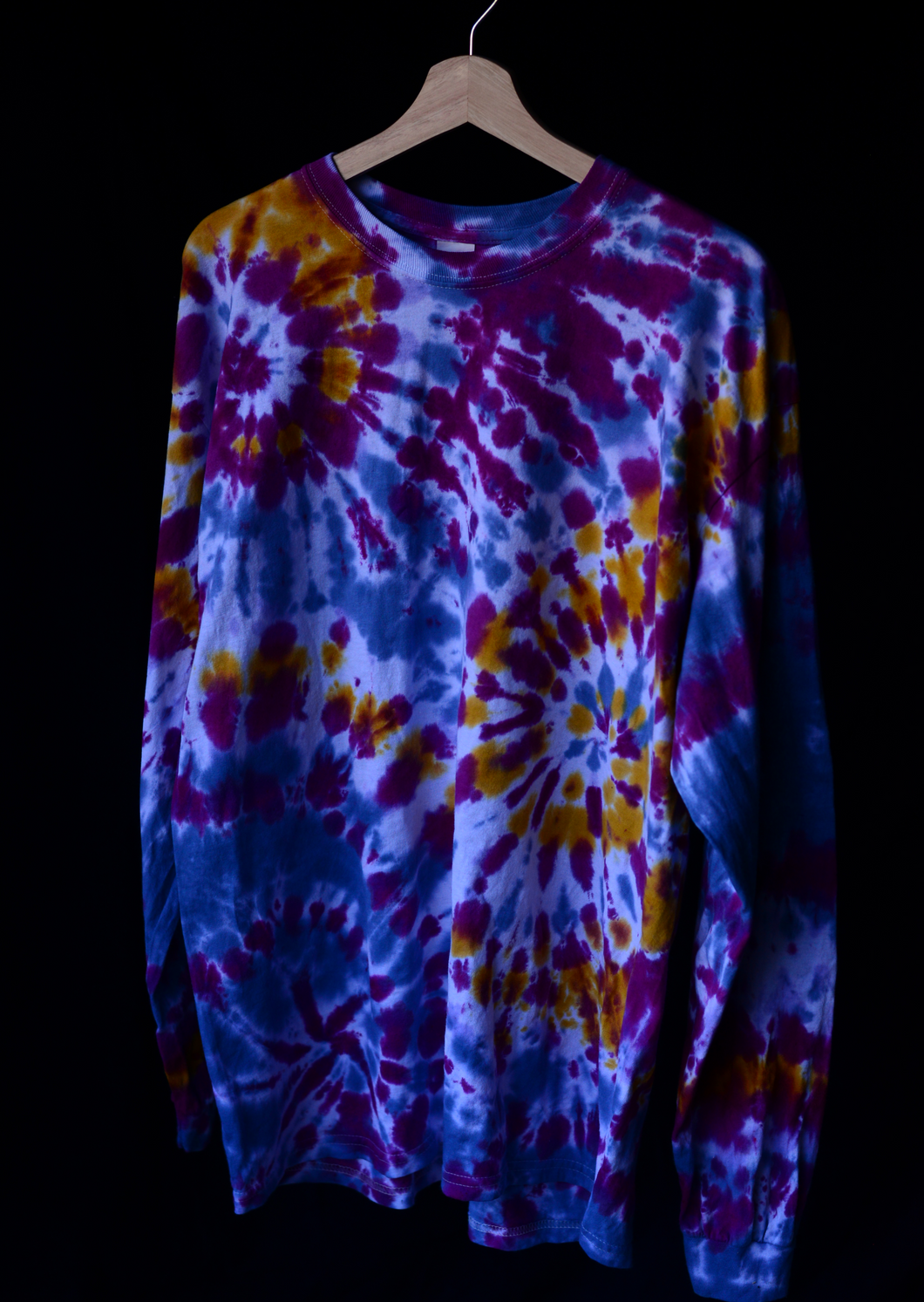 Tie dye shirt with multiple spirals. Colors are deep purple and yellow with a lighter blue.